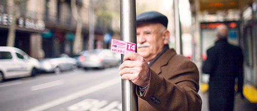 Photo: P. de Grenet Man waiting for the bus at a bus stop, holding the Pink Card in his hand